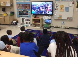 kids in a classroom watching a tele-conference lesson