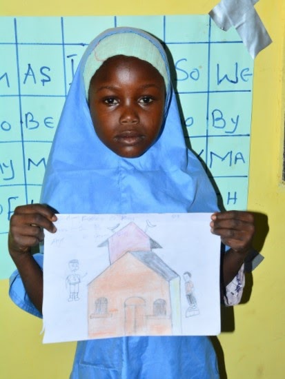 student holding up a drawing of a house