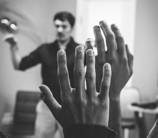 two raised hands, teacher talking in background