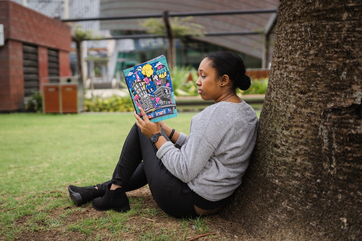 RosieCon Book Celebration girl reading book against a tree