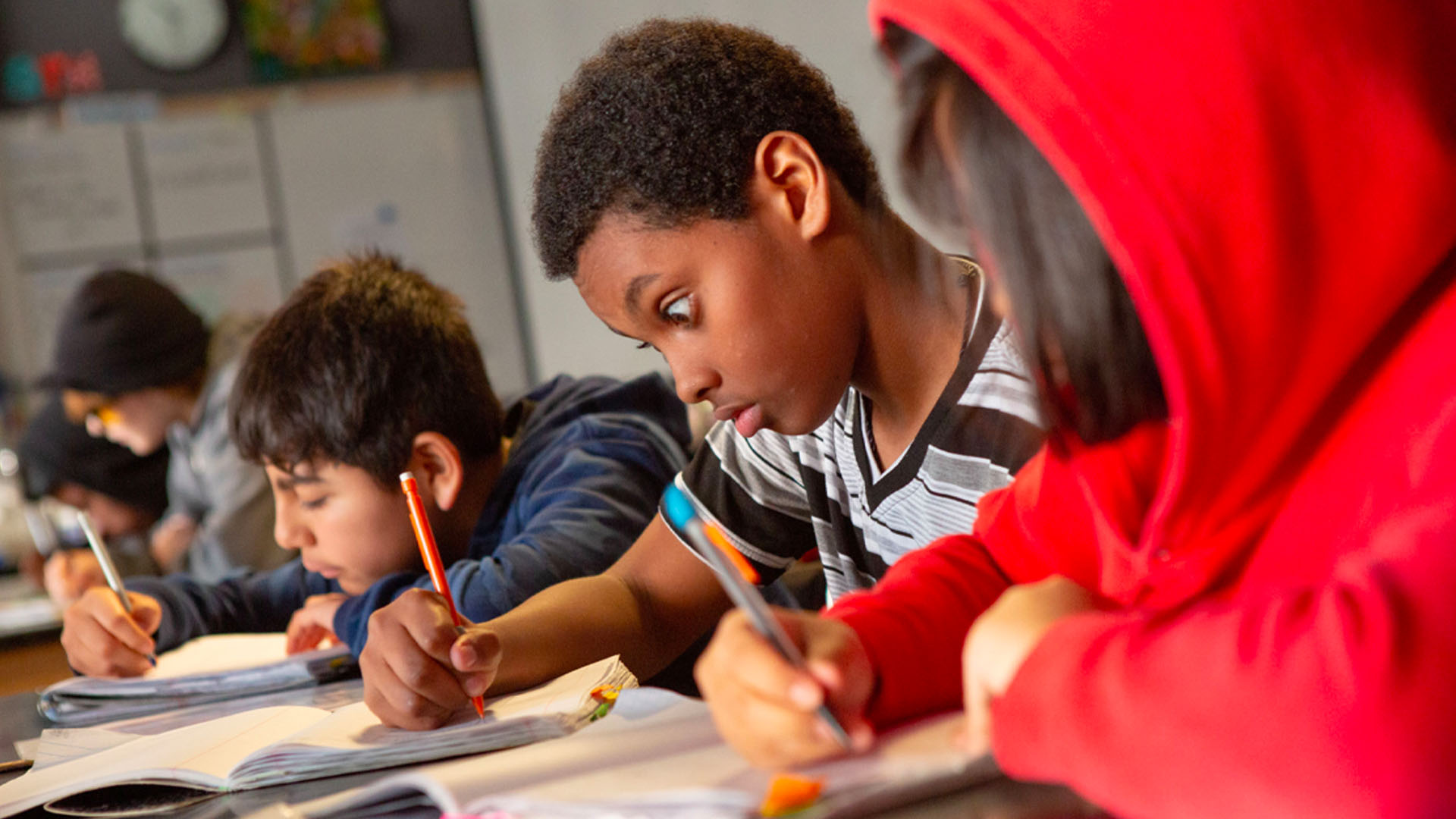 Middle school boy concentrates in science class students writing together