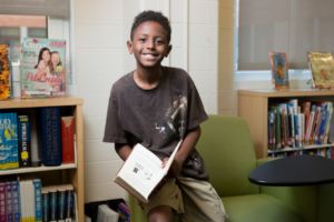 young student holding a book in a library