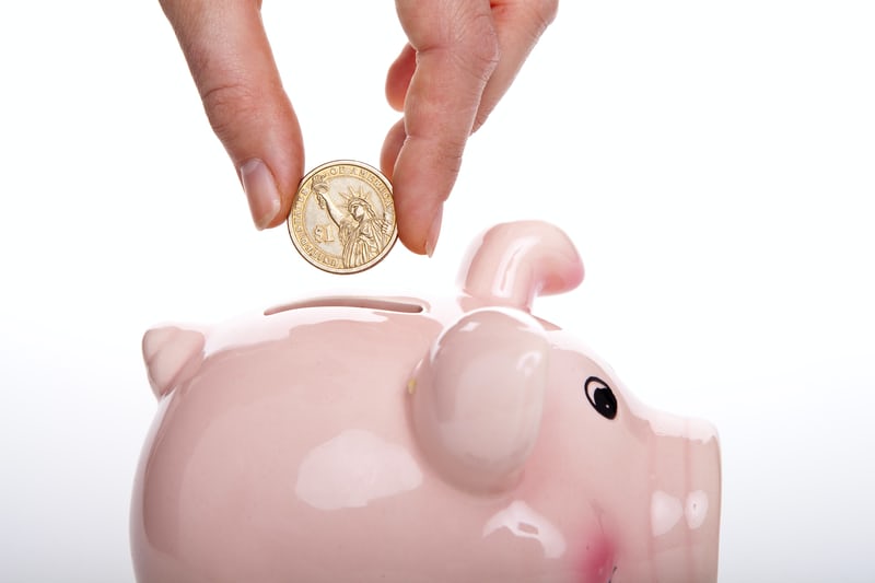 someone putting a quarter in a piggy bank