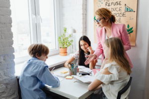A teacher and children at a table.