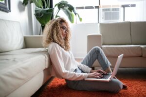 Woman on the floor, using a laptop.