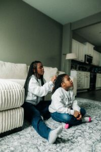 Little girl getting her hair down by another.