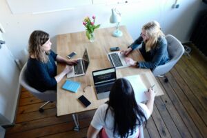 Three people sitting at a table with their laptops open.