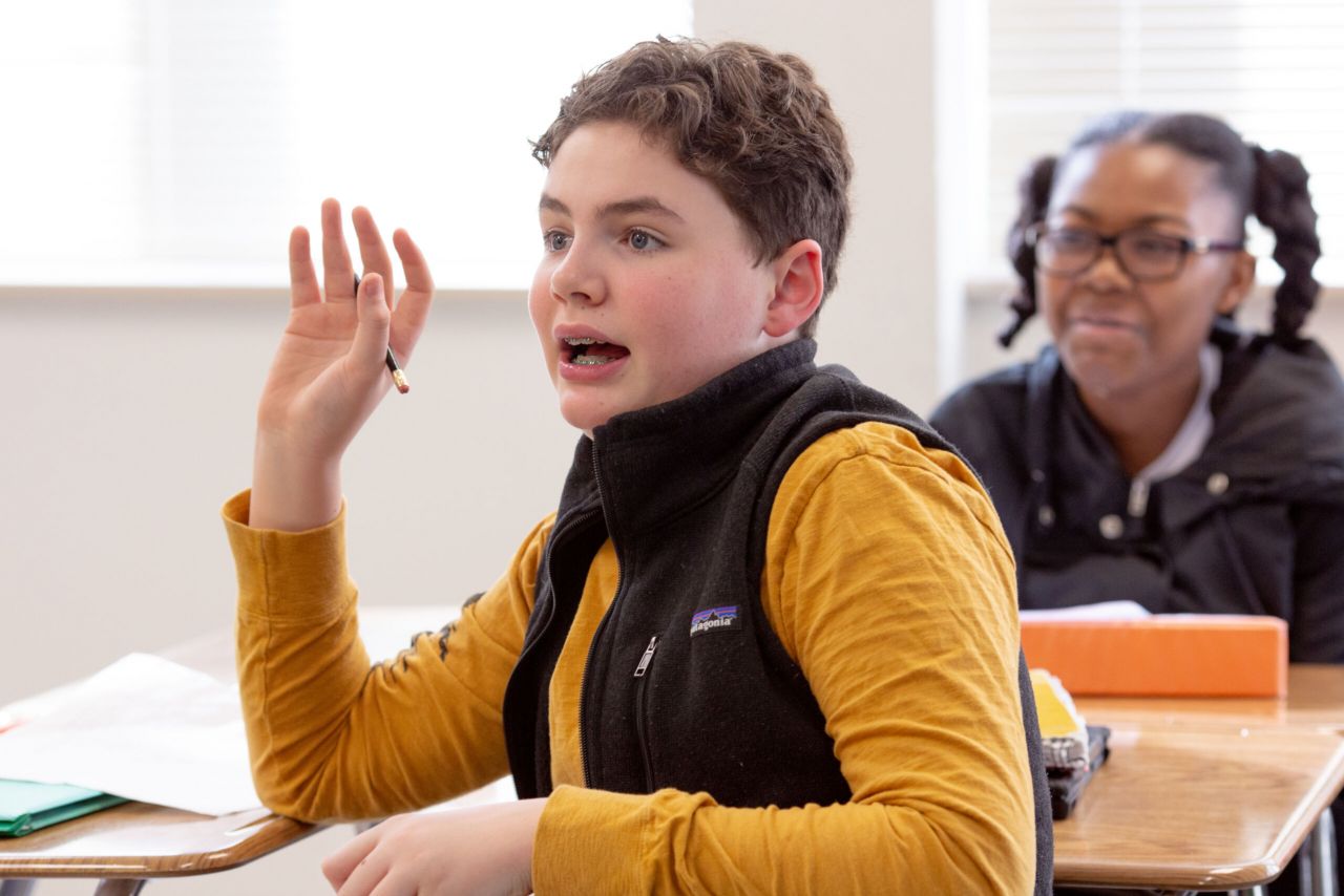 Student raising hand to ask a question.