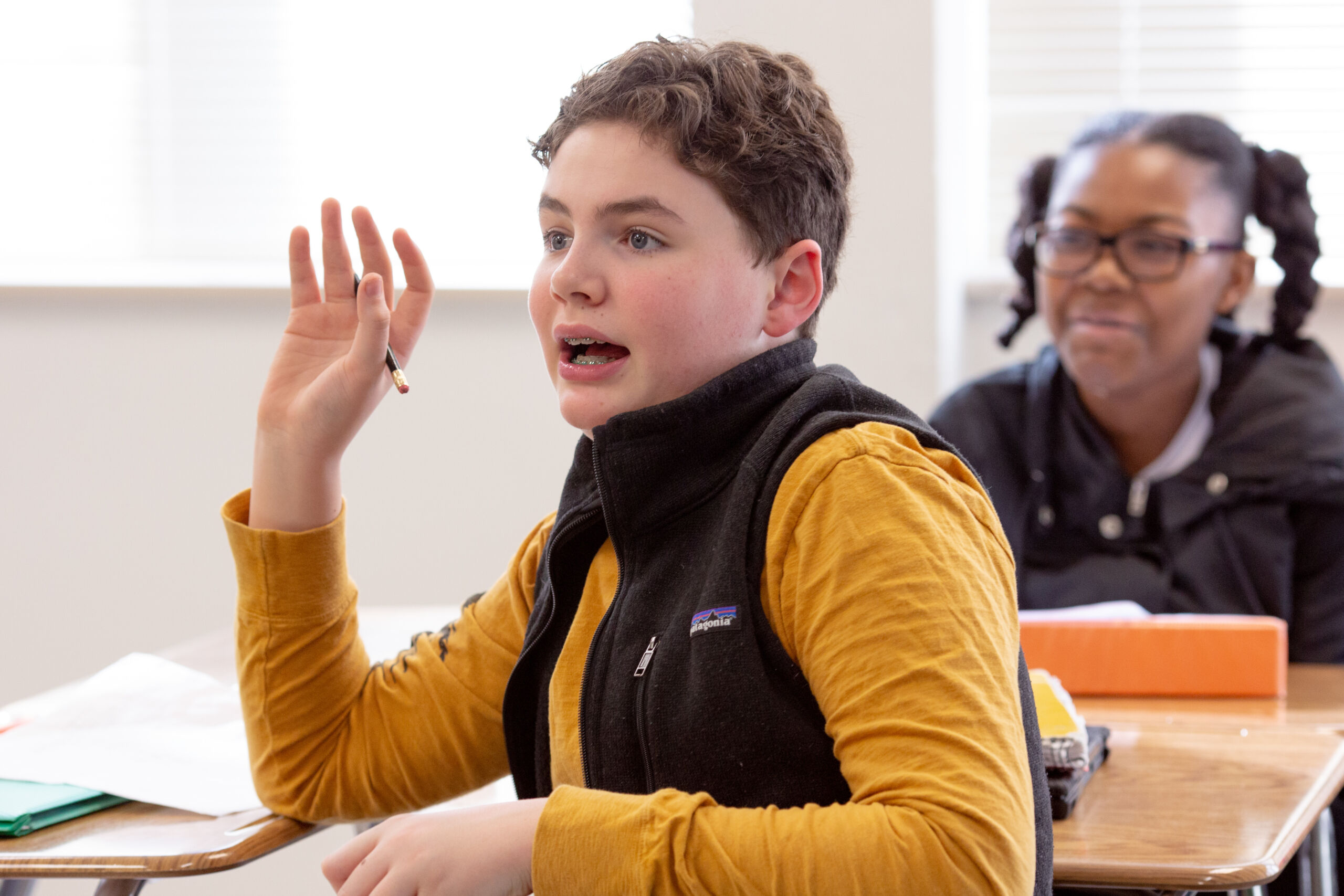 Male middle schooler asks question Student raising hand to ask a question.