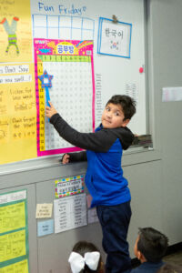 Student in class, pointing out letters in Korean Alphabet.