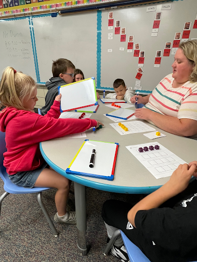 Teacher working with students around a table.