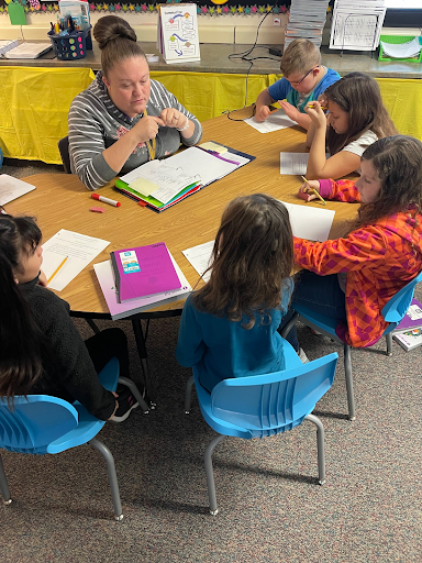 Teacher sitting with students around the table.