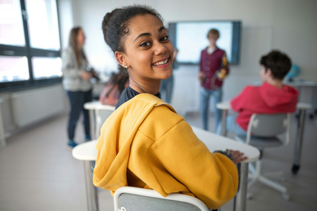 Student posing for a picture, while seated at her desk.