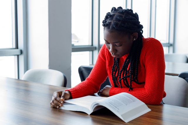 Female student reading a book in a classroom.