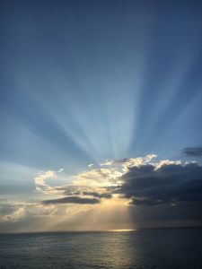 Sun behind the clouds, over the ocean.