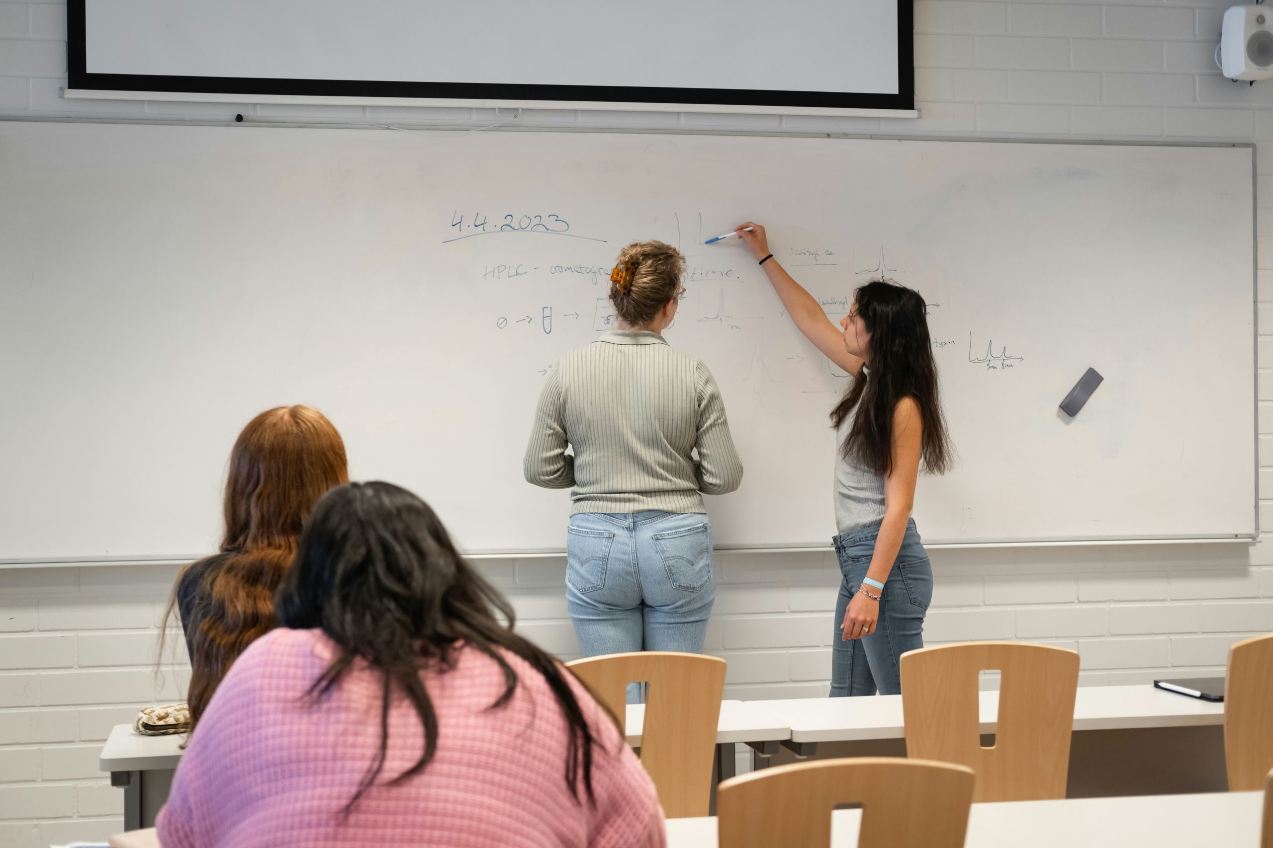 blog april 2024 1 Teachers writing on the whiteboard, while students look on.