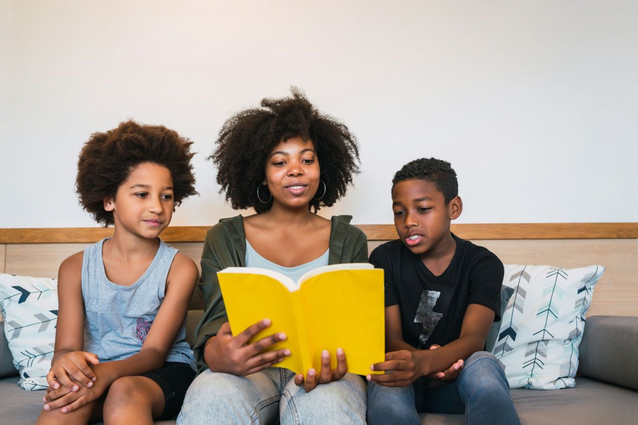 A parent reading a book to two children.