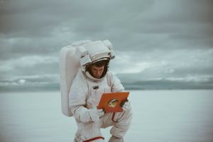 Astronaut crouching and holding a tablet.